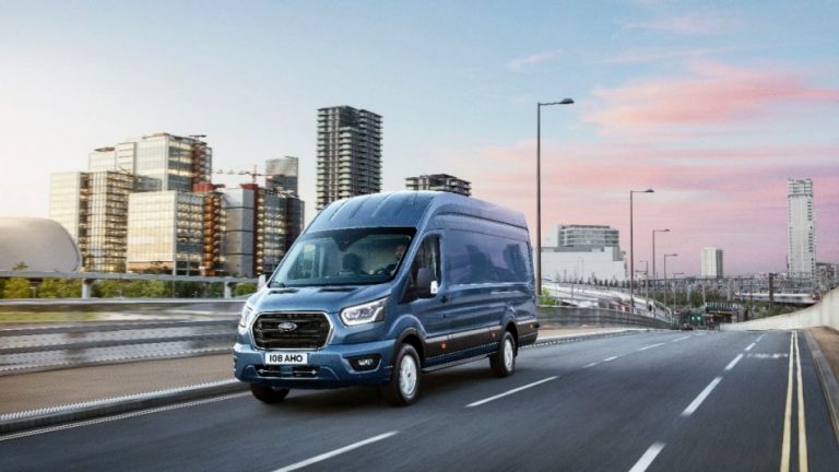 Ein blauer Ford Transit fährt auf einer leeren Autobahn, während die Dämmerung einsetzt und der Himmel allmählich dunkler wird. Die ruhige, weite Straße und die sanfte Abendbeleuchtung unterstreichen die Ruhe und den reibungslosen Ablauf einer Fahrt in den späten Stunden.
