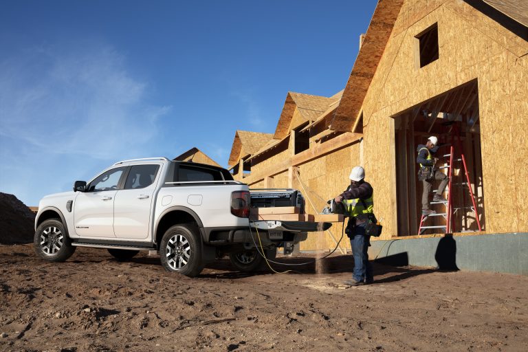 Elektro Ford Ranger auf einer Baustelle, wo er als Arbeitsfahrzeug für den Neubau eines Hauses eingesetzt wird. Zwei Männer in Arbeitskleidung und Sicherheitswesten sind dabei, auf der Baustelle zu arbeiten, während der Ranger als robustes und umweltfreundliches Fahrzeug Materialien transportiert und die Arbeiten unterstützt.